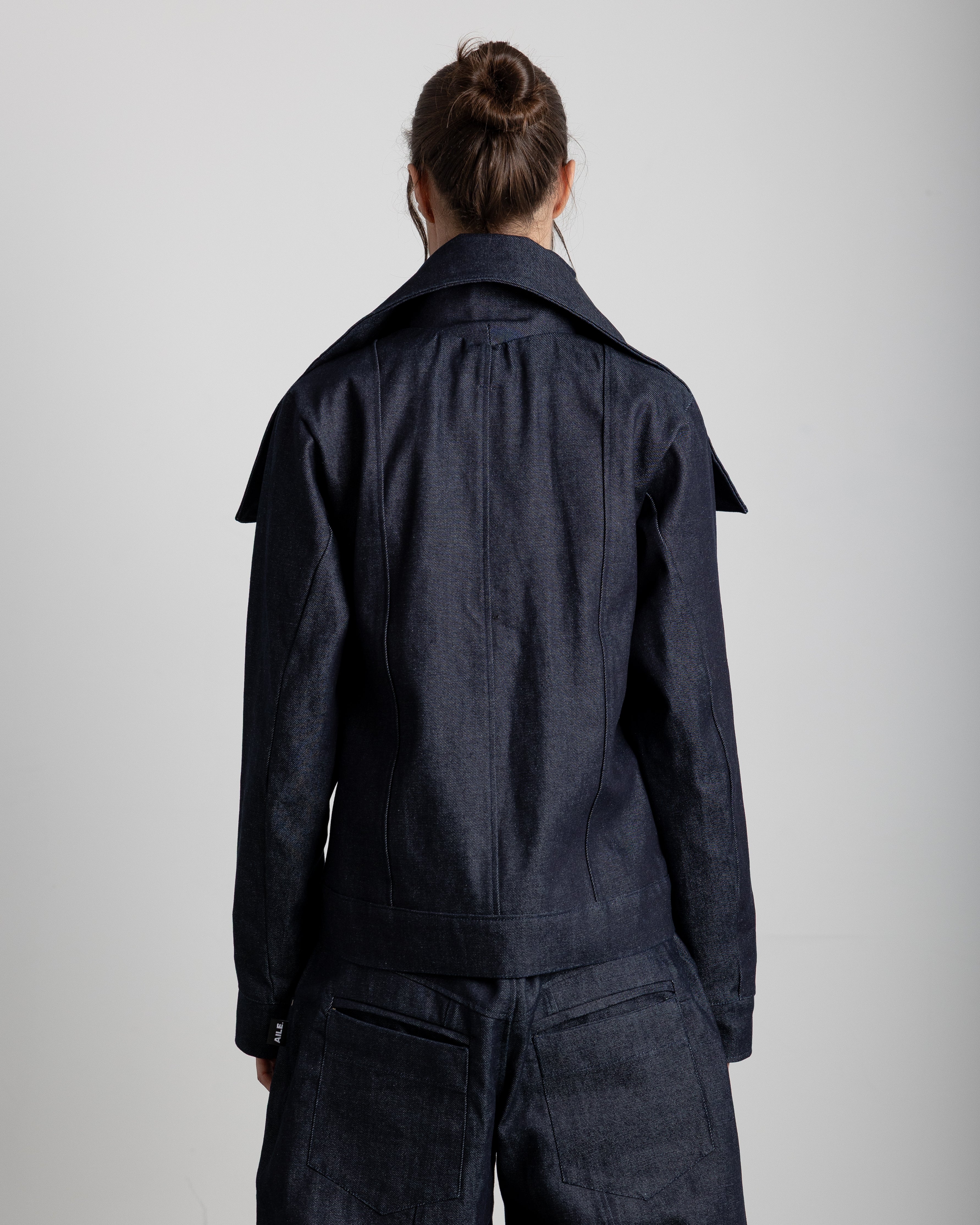 Jacket with a high collar and adjustable lapels. Pleated placket with silver studs covering the zipper. Front pockets.&nbsp;