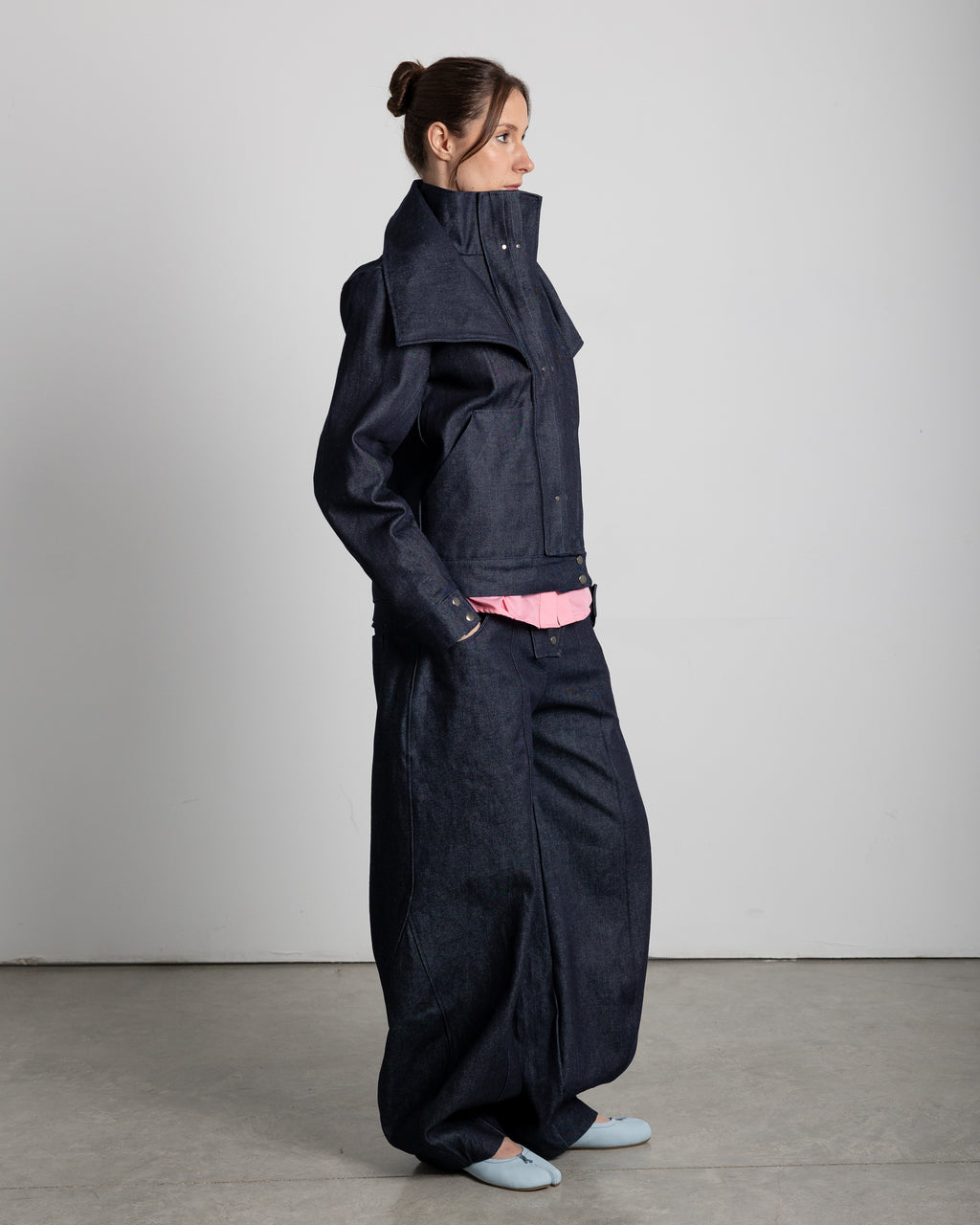 Jacket with a high collar and adjustable lapels. Pleated placket with silver studs covering the zipper. Front pockets.