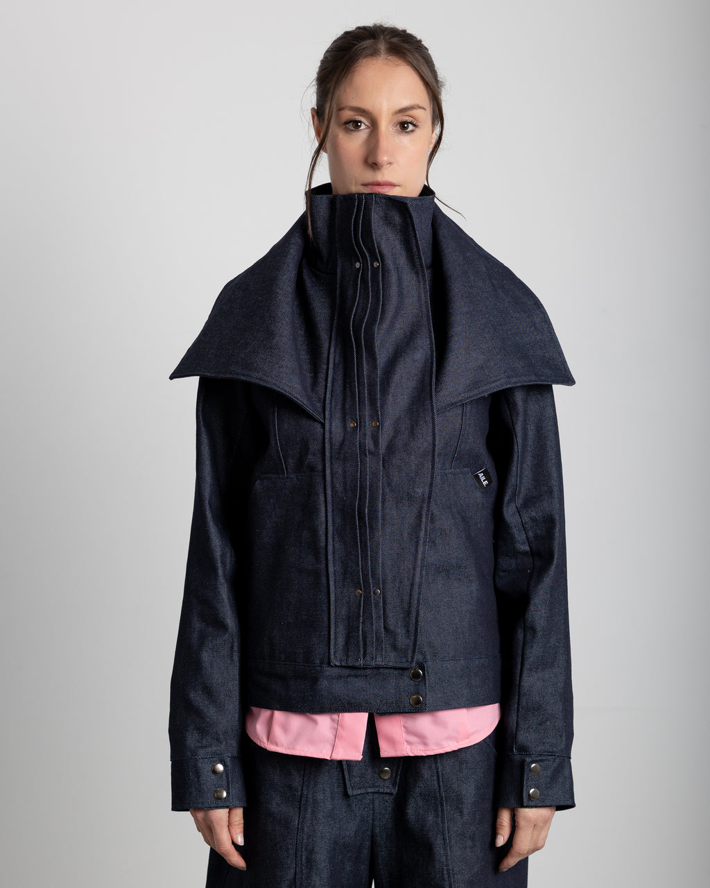 Layered jacket in 100% cotton RAW denim. Jacket with a high collar and adjustable lapels. Pleated placket with silver studs covering the zipper. Front pockets.&nbsp;