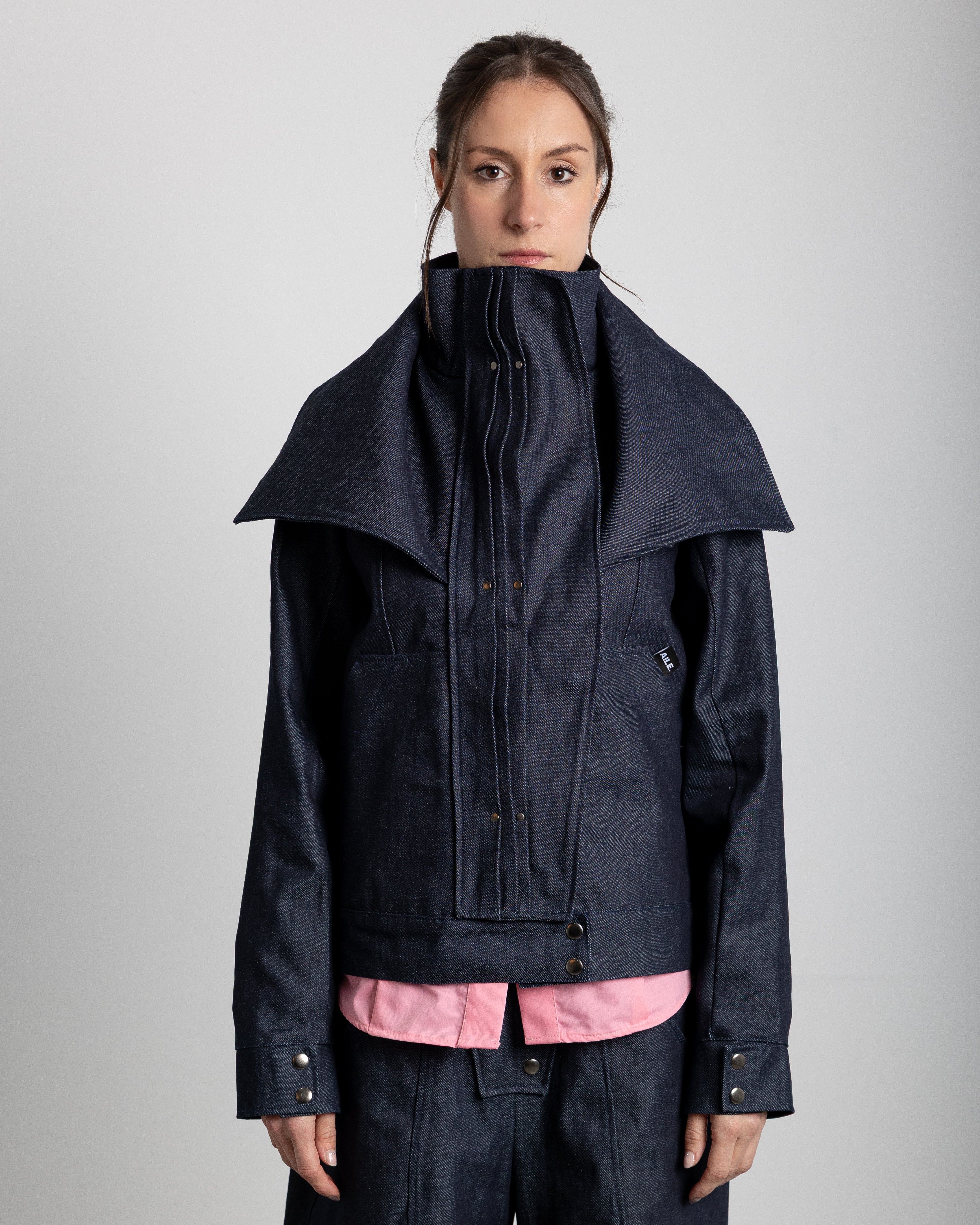 Layered jacket in 100% cotton RAW denim. Jacket with a high collar and adjustable lapels. Pleated placket with silver studs covering the zipper. Front pockets.&nbsp;
